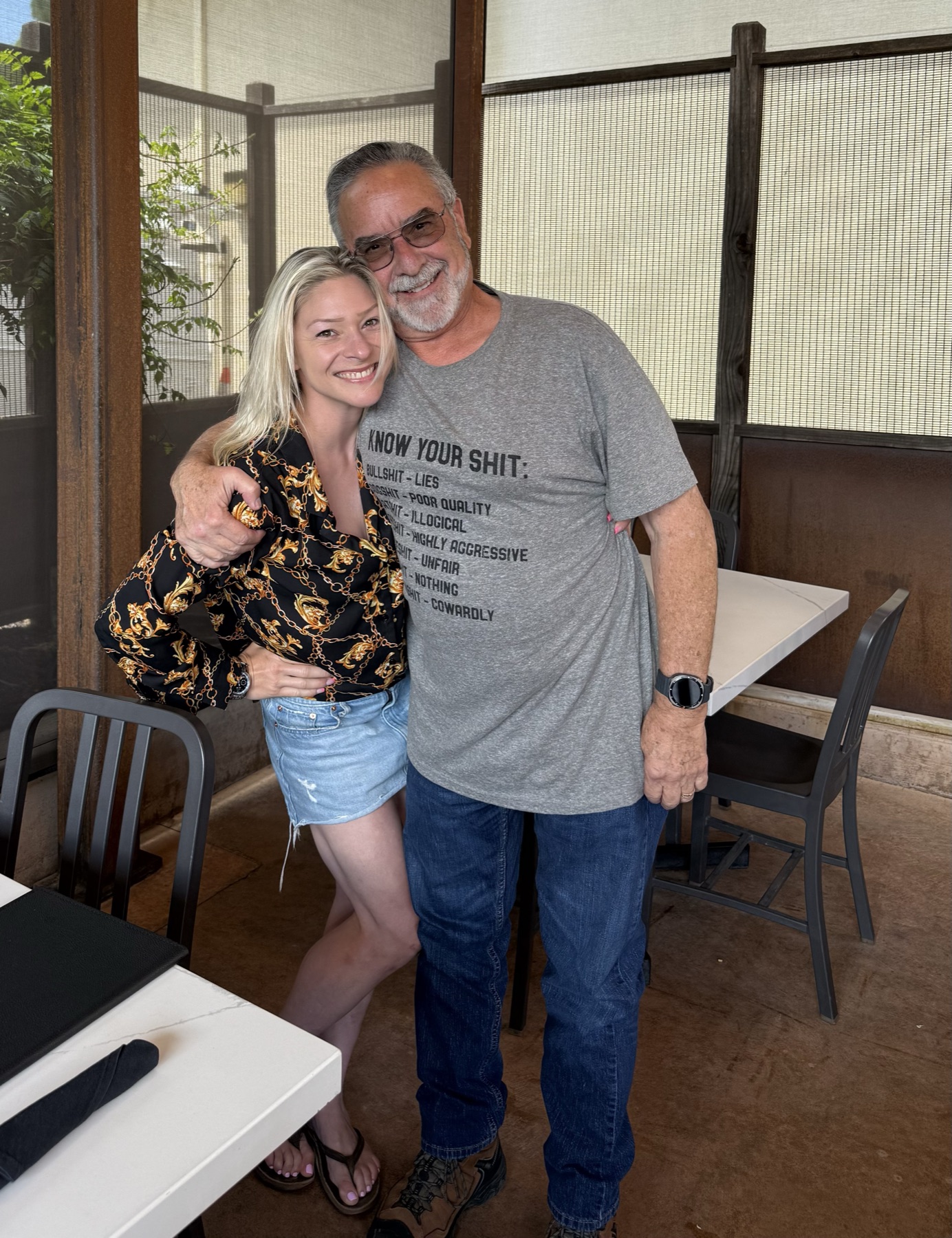 Two people smiling with their arms around each other in a restaurant.